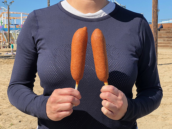 Woman holding two corndogs from Hot Dog on a Stick