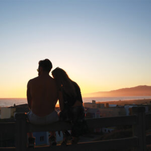 Couple watching sunset on fence at sunset in Palisades Park