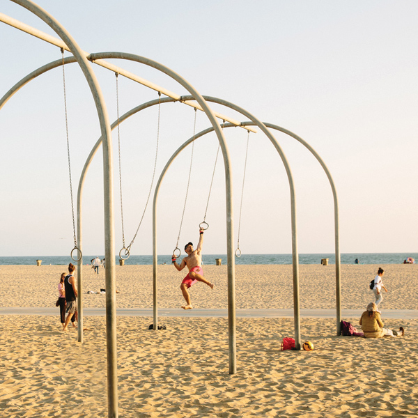 Man swinging on rings at Original Muscle Beach