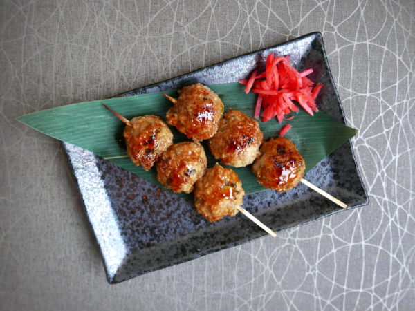 Skewered chicken tsukune (meatballs) crafted with ground chicken leg, brushed with sweet soy yakitori sauce and plated with pickled ginger from Takuma