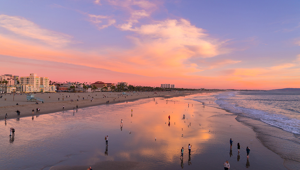 Santa Monica Beach at sunset; sky reflecting off of wet sand; purple, orange and yellow sky