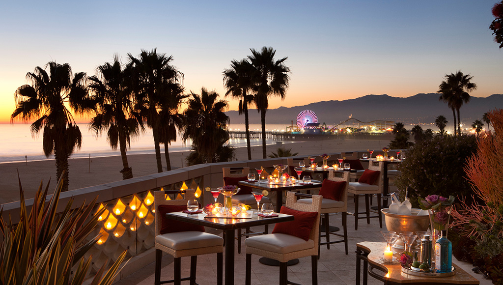 Hotel Casa del Mar patio with luxury high table settings and champagne being chilled to the side; Santa Monica Pier in the background