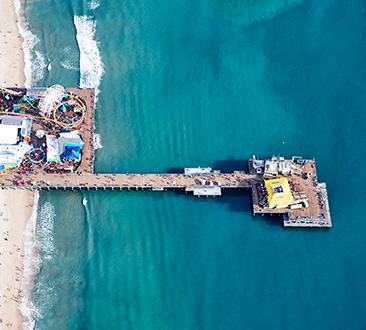 Aerial shot of Santa Monica Pier; blue and green ocean surrounding