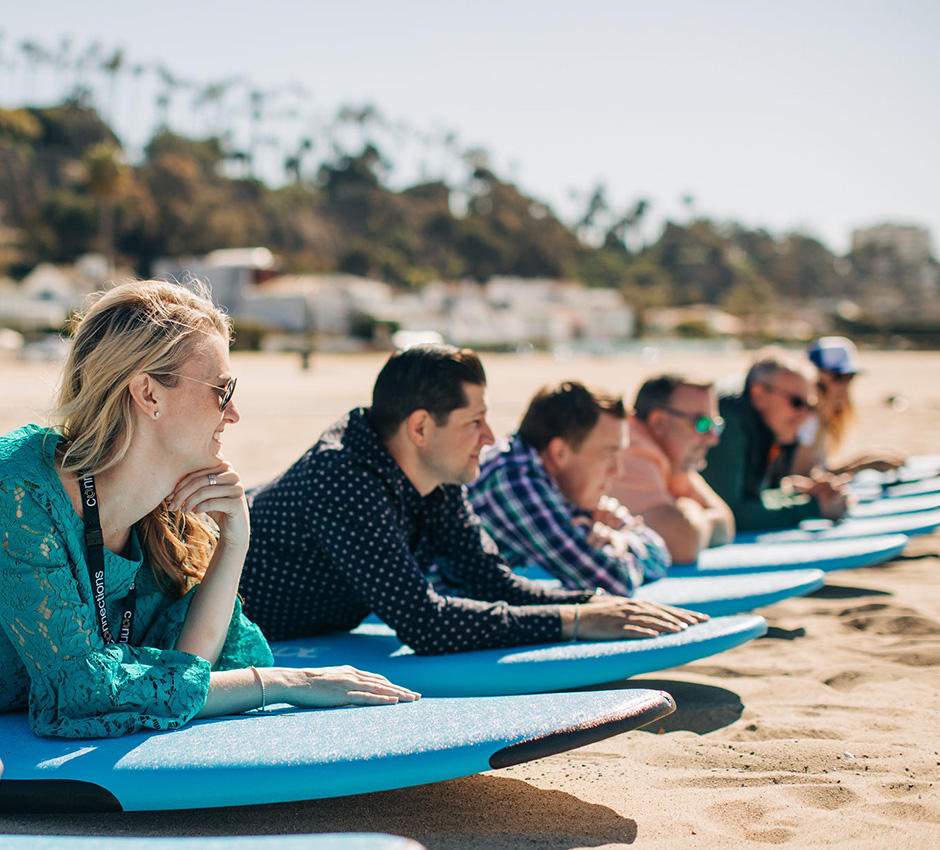 Group of people laying on surf boards for a surf lesson; surf lesson on the beach