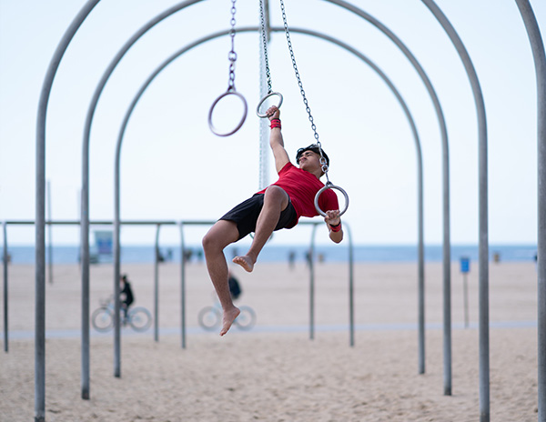 Man swinging through gymnastic rings on Santa Monica Beach