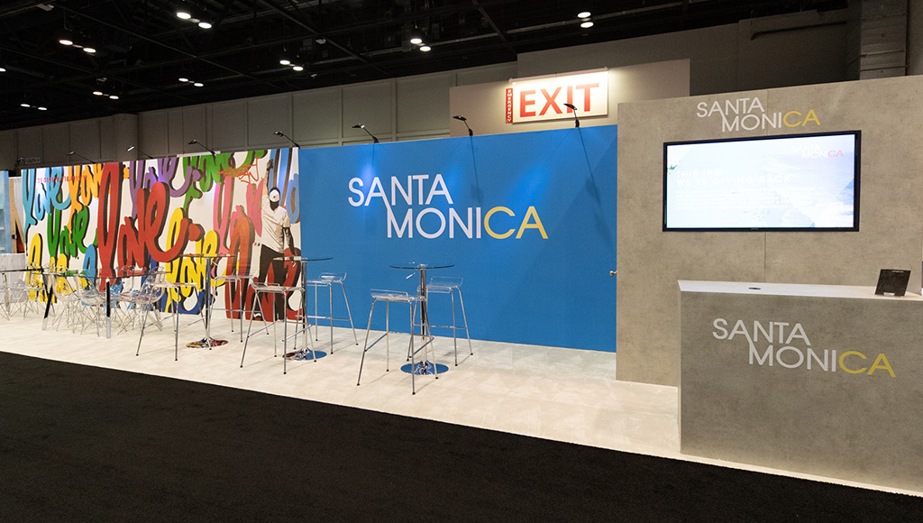 Kiosk with Santa Monica logo and colorful mural at convention