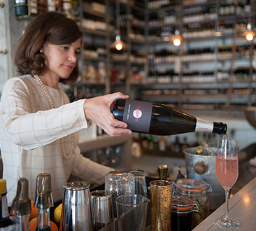 Woman pouring wine into glass at restaurant bar