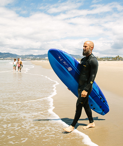 Man on Santa Monica Beach holding surfboard heading into the ocean