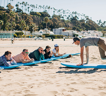 Group of people in professional clothes learning to surf on the beach