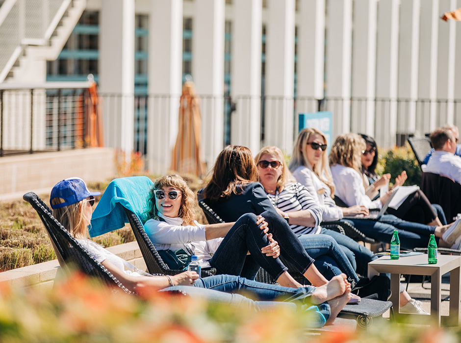People in professional clothes sitting in reclining chairs next to pool