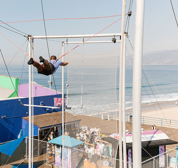 A man swinging above the pier at Trapeze School New York TSNY - Los Angeles in Santa Monica