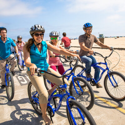 Group of people smiling riding bikes on beach