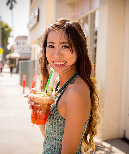 Young woman holding juice and smiling at camera