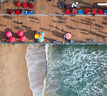 Picture split in half with wooden Santa Monica Pier and beach waves
