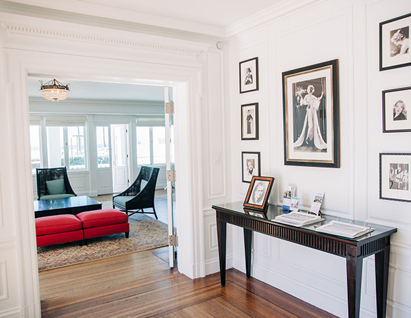 Sitting room of Annenberg Community Beach House; white walls with black and white pictures and a sitting area with red cushions