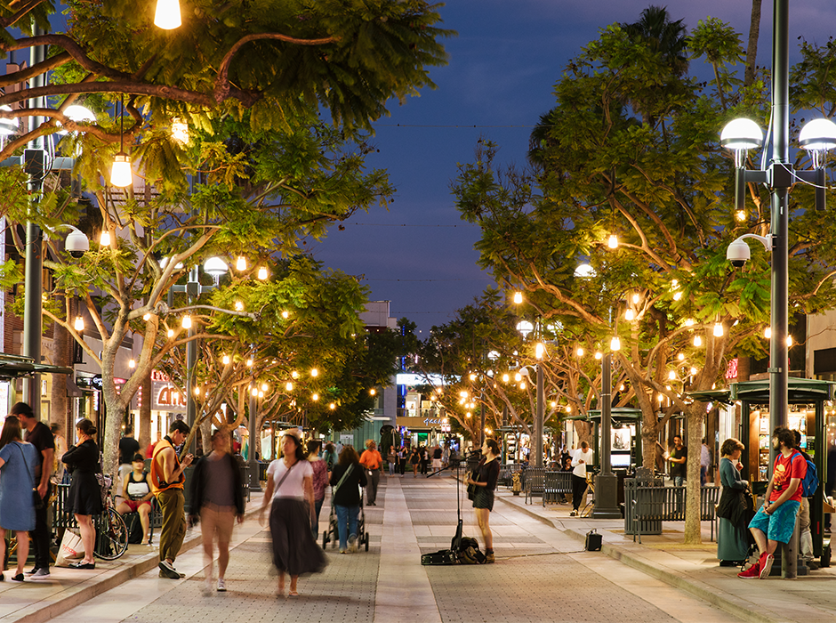 People walking under lite up trees on Third Street Promenade in Santa Monica.