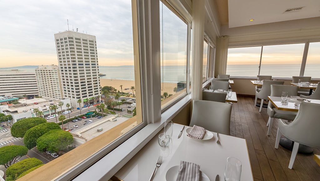 Pastel sunset outside of full-wall windows in penthouse restaurant overlooking Santa Monica Beach and City of Santa Monica