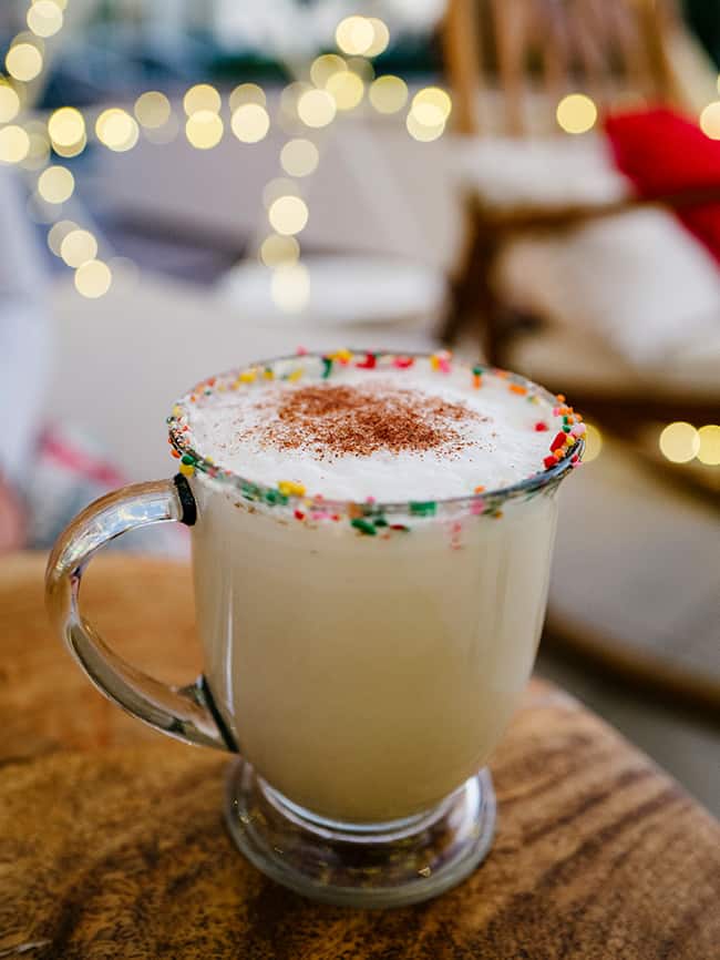 Warm holiday drink in clear mug with brown dusting sprinkled on top and multicolored sprinkles; Santa Monica dining