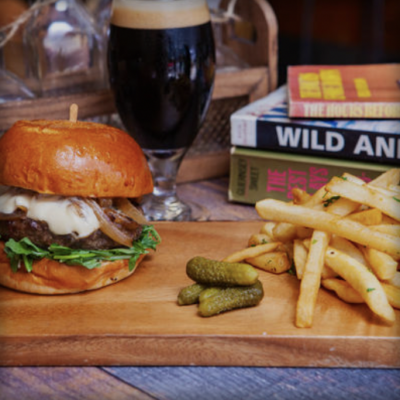 Picture of burger and stout with books in the background; food and drink on table at The Library Alehouse in Santa Monica