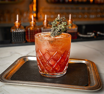 a pink drink with rosemary garnish