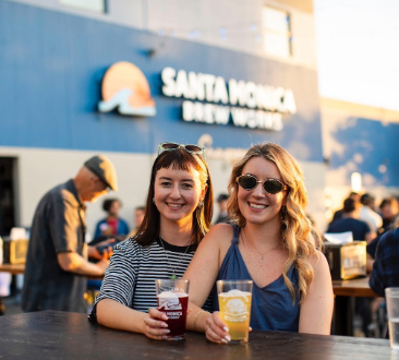 two women in front of are works holding beers